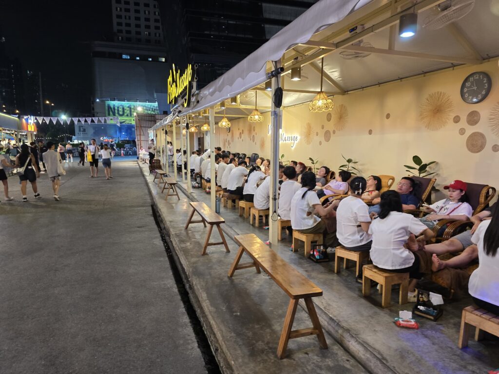 people are relaxing by having massage on the roadside of Jodd Fairs night market